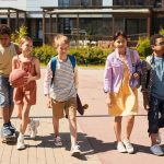 Group of children enjoying school holiday fun in Yanchep, walking with a basketball and skateboard on a sunny day